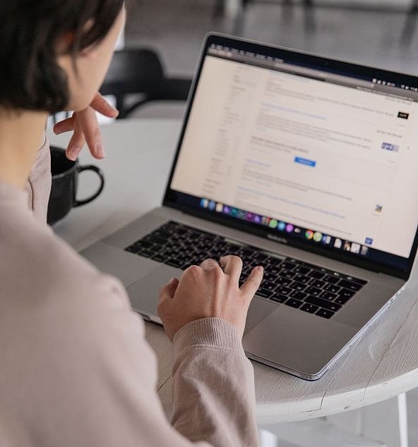 Person sitzt am Laptop und blickt auf den geöffneten Browser