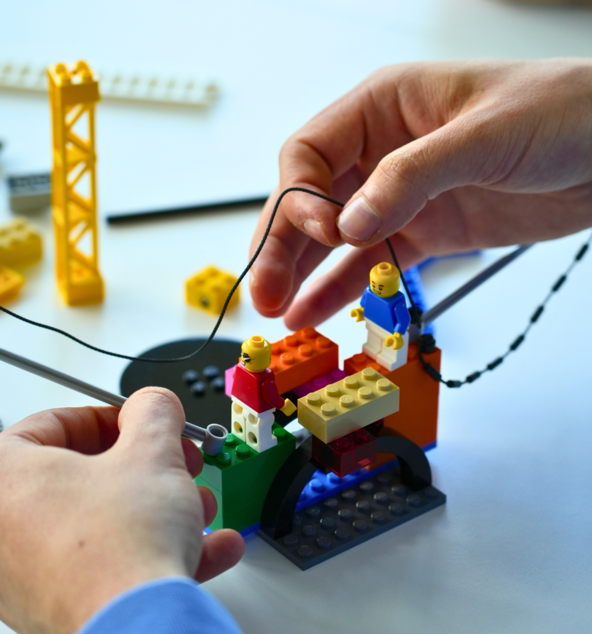 Hände bauen ein LEGO-Modell zusammen